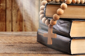 Wall Mural - Dramatic bright light beam shining on an old bible with a rosary laying in front of it.