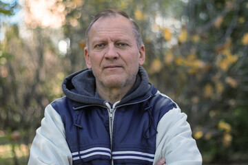 man, mature, middle-aged, 60 years old, with gray hair, with wrinkles, waist-length portrait against the background of nature