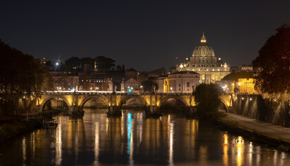 View of the St. Peter's basilica dome with the Vittorio Emanuele II bridge at the foreground, Vatican City, Rome. Light reflection in the water of the Tiber river in the late evening.