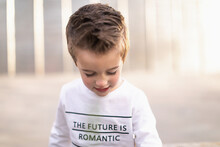 Young Boy Looking Down Wearing Shirt That Says The Future Is Romantic