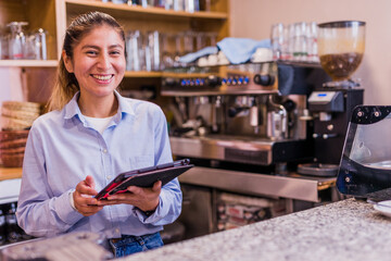 Peruvian entrepreneur doing inventory with touchscreen. Young Latinx businesswoman