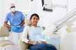 Cheerful hispanic female patient sitting in dental chair waiting for medical examination