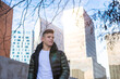 © Cavan Images - Young man walking hands on pocket against modern city buildings