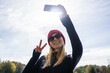 © Cavan Images - Canadian young woman in park using smartphone to take selfie