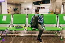 Pre-teen Boy Wearing Mask Uses Phone Sitting In Airport Terminal