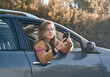 © Cavan Images - girl smiling in the car window while consulting mobile phone to talk with her friends.