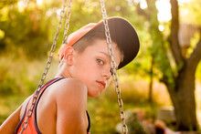 Pensive Teenager On A Swing In Summer