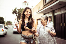 Young Attractive Mexican Woman Walks Her Grandma Across Local Road