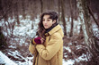 © Cavan Images - Girl with freckles stands in snow covered forrest keeping warm