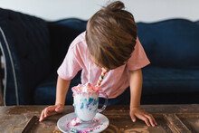Boy Drinking A Colorful Milk Shake In Front Of A Vintage Blue Couch.