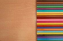 Row Of Colored Pencils On A Wooden Background.