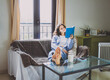 © Cavan Images - young woman on the sofa reading a book with a coffee