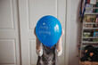 © Cavan Images - Tween girl holding blue birthday balloon in front of face