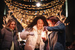 © Cavan Images - Happy female friends igniting sparklers in city during Christmas