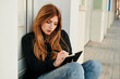 © Cavan Images - Young woman writes in her notebook while she is sitting on the street