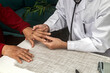 © Cavan Images - Doctor examining the hand of an elderly man with osteoarthritis