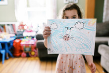 A Proud Little Girl Holding Up Her Drawing Of A Lady Bug In Her Room