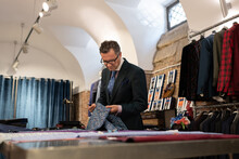 Mature Tailor Examining Ornamental Cloth