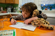© Cavan Images - Little boy holding a stuffed Animal while writing