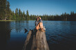 © Cavan Images - Blonde Woman Poses on a log over water at Sunset.