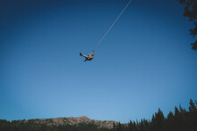 Boy On Rope Swing Files High Against The Bright Blue Sky