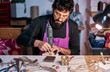 © Cavan Images - Craftsman jeweler working with a drill at the work table