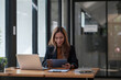 © Natee Meepian - Asian woman working digital tablet and laptop computer. Smiling female busy working at office