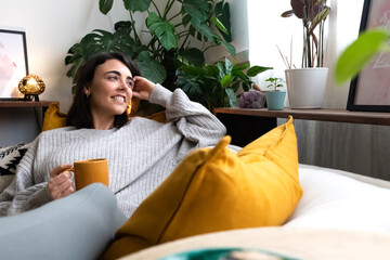 happy young woman relaxing at home with tea looking out the window. copy space.