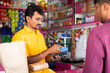 Indian customer making payment using credit card at groceries or Kirana shop - concept of digital or cashless payment, finance and Small business.