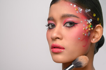 woman wearing pink makeup and holding a blush brush