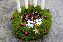 Advent Candlestick Made Of Moss And Cones. Shiny Red Balls And White Four Candles. Table Decoration With Two White Reindeer Made Of Wooden White Plywood. Star. Outdoors In The Snow Acorn