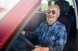 © Parilov - Happy senior man pensioner in round sunglasses smiling and driving car