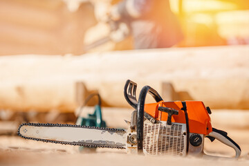 Poster - Closeup Chainsaw on background of sawmill logging with glare of sun