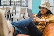 © chokniti - Young Thai asian woman lying on sofa bed, using digital computer tablet to relax and online working