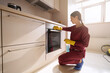 © Viacheslav Yakobchuk - Professional cleaner wiping electric oven control panel with microfiber cloth