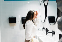 Woman fixing hair near mirror in restroom