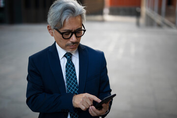 Wall Mural - Senior businessman outdoors. Middle-aged businessman using the phone.