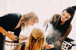 © Westend61 - Female hairdresser spraying hairspray on bride while standing by make-up artist