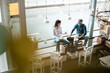 © Westend61 - Team working together while sitting by window at cafe
