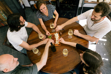 top view of friends around the table with white wine and tapas appetizer food