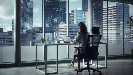 Canvas Print - Successful Caucasian Businesswoman Sitting at Her Desk Working on Laptop Computer in Big City Office. Confident Corporation CEO Plan Investment Strategy for Disruptive e-Commerce Startup. Back View