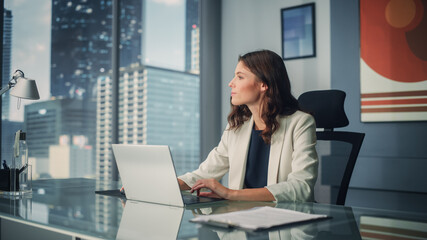 Poster - Portrait of Young Successful Caucasian Businesswoman Sitting at Desk Working on Laptop Computer in City Office. Ambitious Corporate Manager Plan Investment Strategy for e-Commerce Project.
