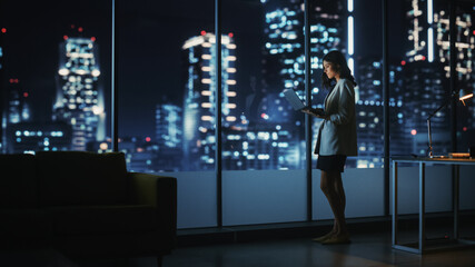Poster - Big City Modern Office at Night: Successful Young Businesswoman Standing and Using Laptop. Beautiful Female Digital Entrepreneur Thinking of Investment Strategy for e-Commerce Project.