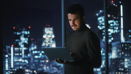 Aufkleber - Big City Modern Office at Night: Successful Businessman Standing and Using Laptop. Handsome Male Digital Entrepreneur Thinking of Investment Strategy for e-Commerce Project.