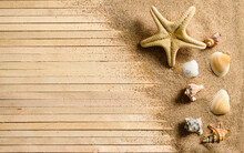 Starfish And Several Seashells On The Sand On A Wooden Background. Summer Theme. Top View, Selective Focus On Seashells.