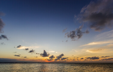 Wall Mural - dusk sky over sea in the evening after sundown with colorful sunlight blue sky clouds on twilight