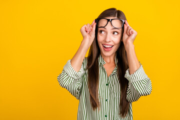 Poster - Photo of young cheerful excited woman hands touch eyeglasses look empty space curious isolated over yellow color background