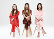 © Raisa Kanareva - Three beautiful girlfriends dressed in pajamas sit on chairs and pose for the camera.