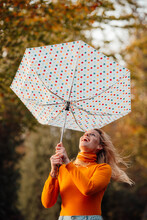 Cheerful Woman Looking At Upside Down Umbrella