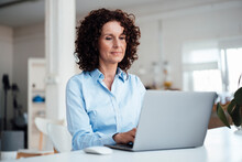 Mature Businesswoman Using Laptop At Desk In Office